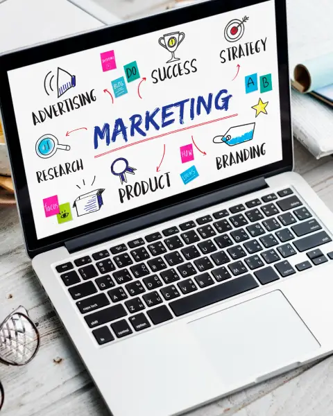 A laptop displaying a marketing mind map, featuring terms like advertising, strategy, and branding illustrated with colorful icons