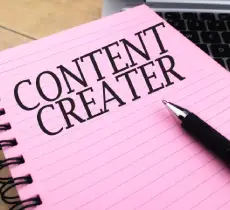 Selective focus image of pen and book with CONTENT CREATER wording.