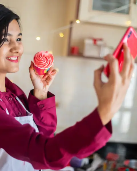 Christmas Celebration, Happy Young Indian Girl Doing video Call On Smart Phone Showing Cup Cake, Distance Celebration Due To Covid Pandemic.